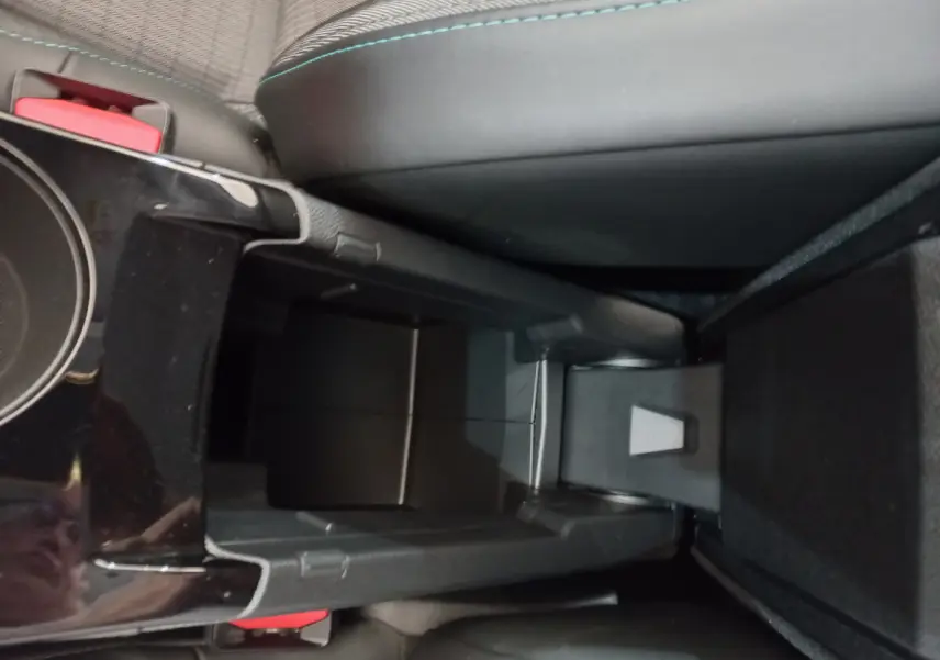 Vue rapprochée de la console centrale noire entre les sièges avant d'une Peugeot 208 blanche PureTech 100 S&S Allure 2021.