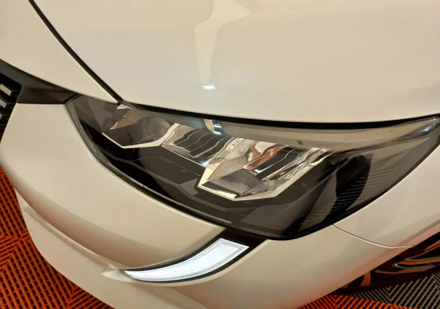 Gros plan sur le phare avant droit blanc d'une Peugeot 208 PureTech 100 S&S Allure 2021, détails LED visibles.