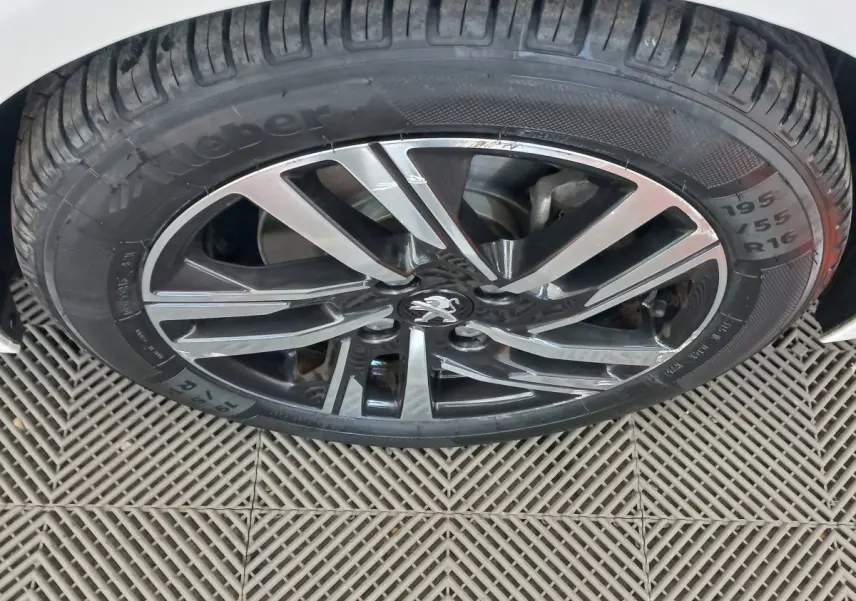 Gros plan sur la roue avant droite blanche d'une Peugeot 208 PureTech 100 S&S Allure avec jante alliage noire et argent.