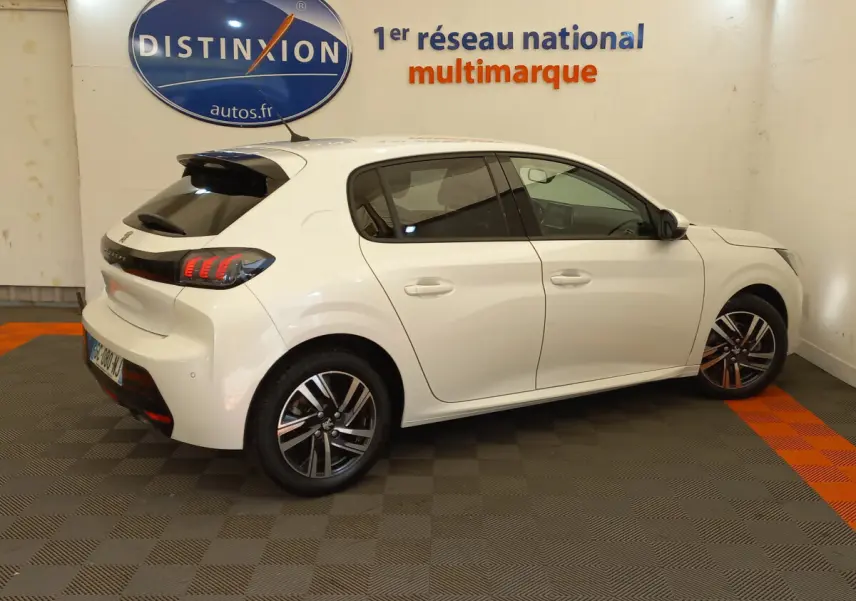 Vue côté gauche d'une Peugeot 208 blanche PureTech 100 S&S Allure avec feux arrière LED et jantes alliage.