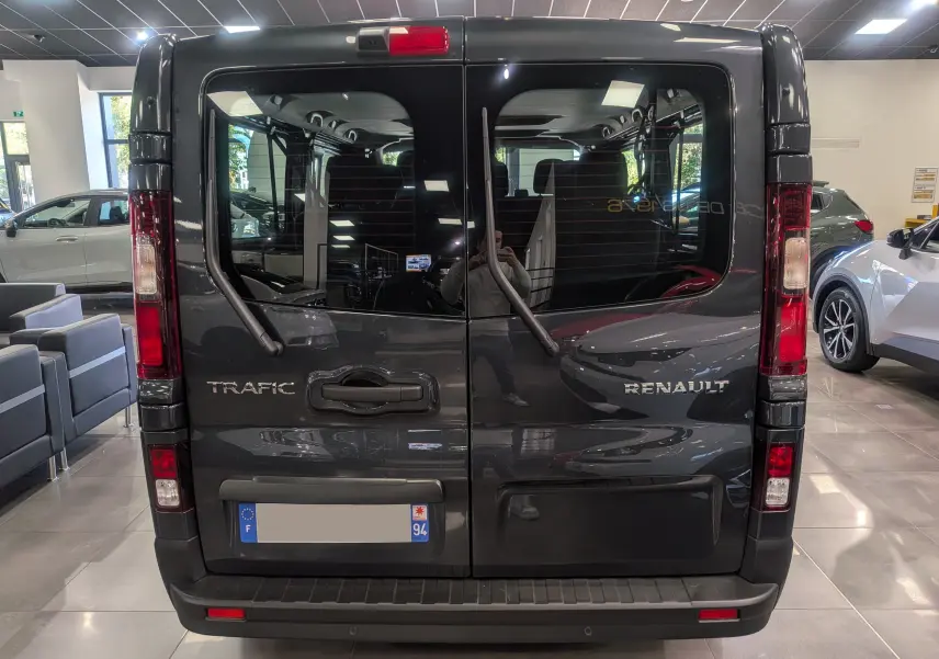 Vue arrière du Renault Trafic Combi gris Comète 2025, avec portes vitrées et essuie-glaces verticaux visibles.