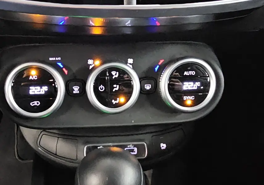 Gros plan sur la console centrale du FIAT 500X bleu 2024, montrant les commandes de climatisation digitales et la boîte automatique.
