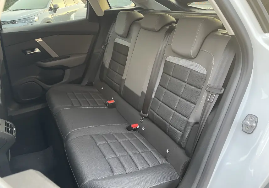 Vue intérieure côté arrière droit montrant les sièges arrière noirs en tissu et cuir de la Citroën C4 blanche 2025.