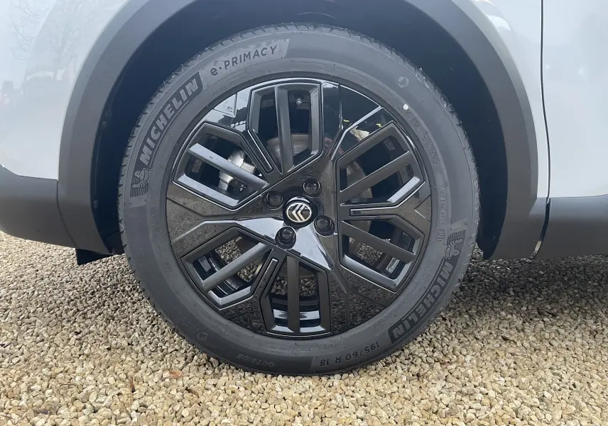 Gros plan sur la roue avant droite de la Citroën C4 blanche, jante noire au design géométrique distinctif.