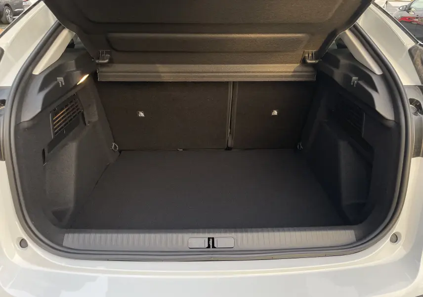 Coffre ouvert vu de l'arrière d'une Citroën C4 blanche Okenite avec toit noir, montrant un espace de chargement propre et vide.