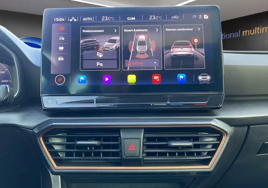 Vue rapprochée de l’écran tactile central et des aérateurs du tableau de bord intérieur d’une CUPRA Leon 2023 noire.