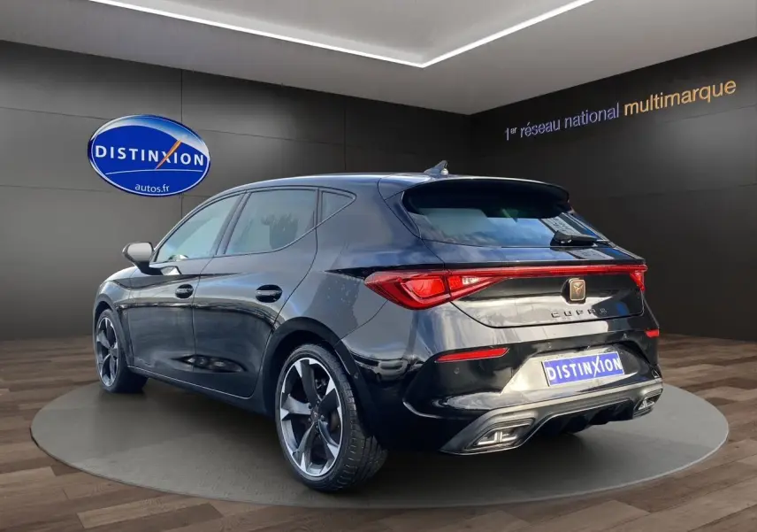 Vue 3/4 arrière droite d'une CUPRA Leon noire 2023 avec jantes bi-ton et feux arrière LED intégrés.