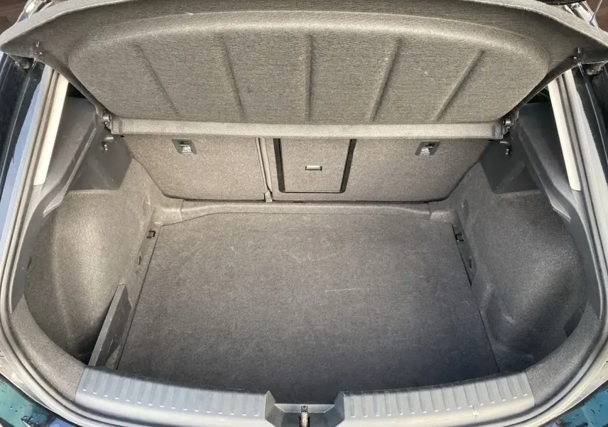 Coffre ouvert vu de dessus d'une CUPRA Leon noire 2023, montrant l'espace de rangement intérieur vide et la trappe arrière.