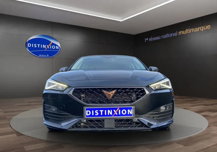 Vue avant d'une CUPRA Leon noire 2023 avec calandre distinctive et phares LED allumés dans un showroom.