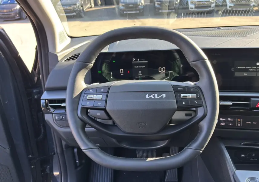 Vue intérieure centrée sur le volant cuir multifonctions du Kia Sportage gris eclipse, tableau de bord numérique visible.