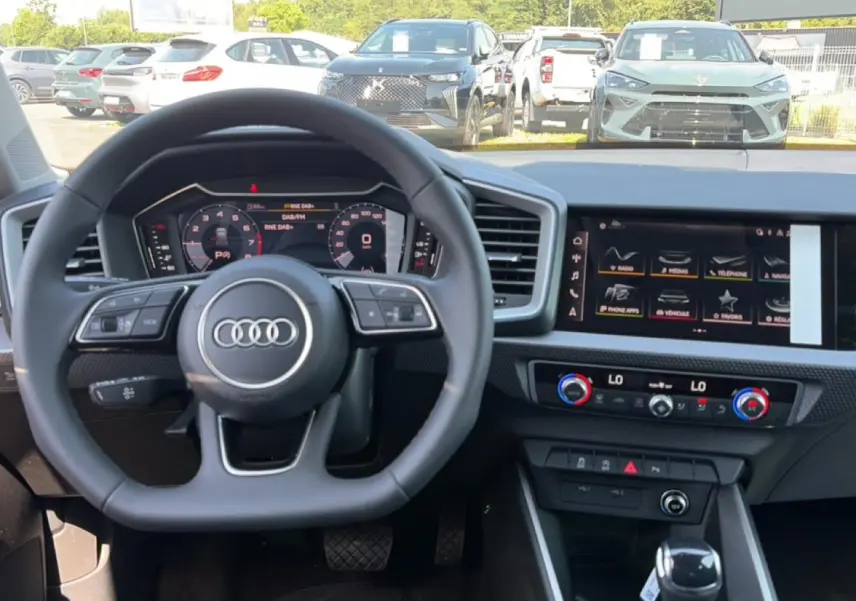 Vue intérieure centrée sur le volant cuir multifonction et l'écran tactile du tableau de bord de l'Audi A1 Sportback 2026.