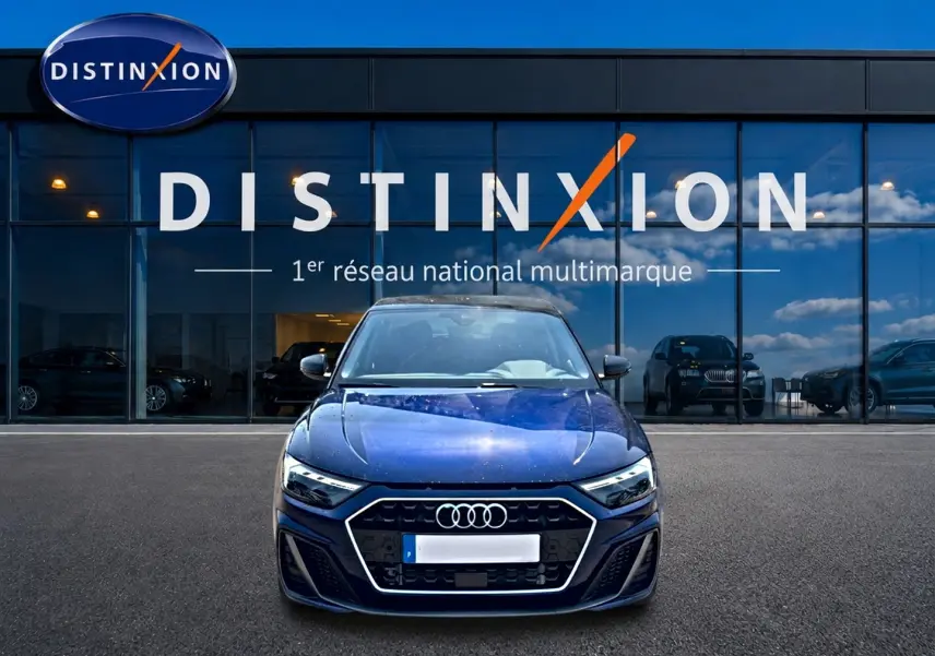 Audi A1 Sportback bleu foncé vue de face devant une vitrine avec logo Distinxion en arrière-plan.