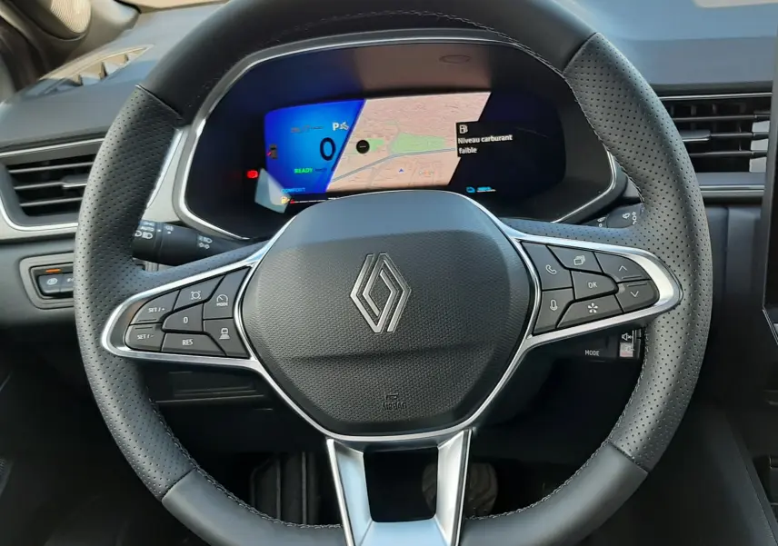 Vue intérieure centrée sur le volant en cuir perforé noir de la Renault Symbioz 2024 avec tableau de bord numérique affichant la navigation.