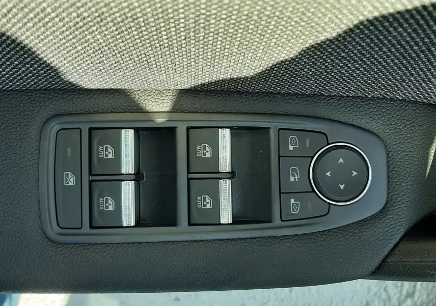 Gros plan sur les commandes des vitres électriques et des rétroviseurs du côté conducteur d'une Renault Symbioz gris Rafale.