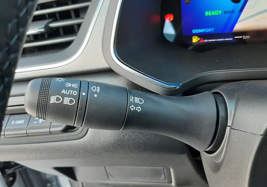 Gros plan sur la commande des phares et clignotants à gauche du volant du Renault Symbioz gris Rafale, tableau de bord numérique visible.