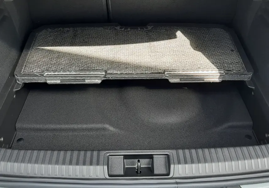 Coffre ouvert vu de l'arrière d'une Renault Symbioz gris Rafale, avec tapis de protection partiel visible.