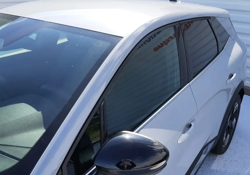 Vue de côté droit avant d'un Renault Symbioz gris Rafale avec rétroviseur noir brillant et vitres teintées.