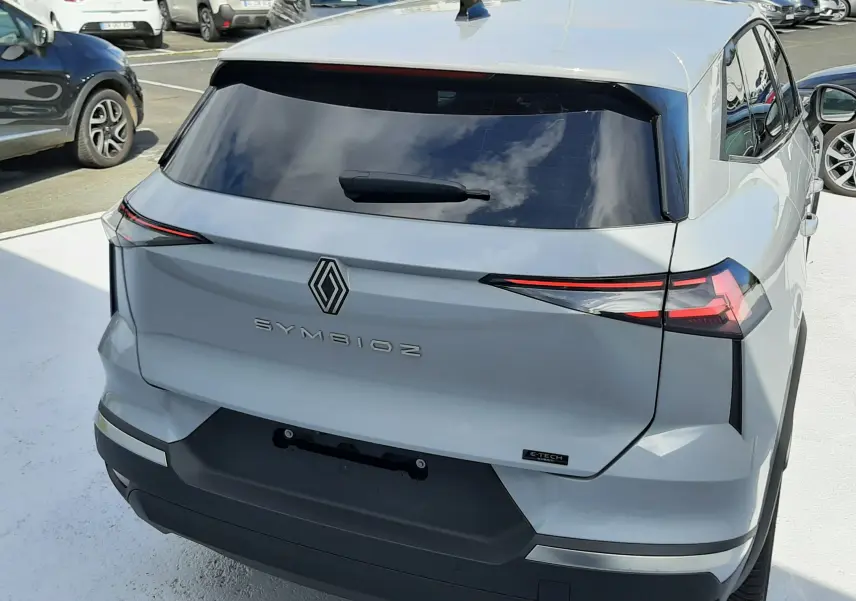 Vue arrière en léger 3/4 droit du Renault SYMBIOZ gris Rafale, soulignant ses feux arrière fins et sa lunette teintée.