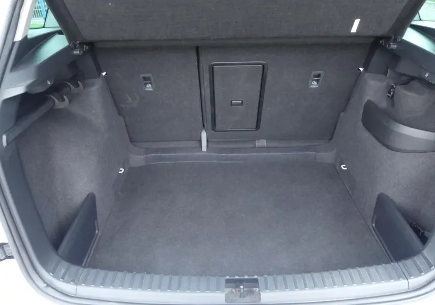 Coffre ouvert du Skoda Karoq 2024, vue intérieure montrant un espace de rangement gris foncé avec trappe centrale.