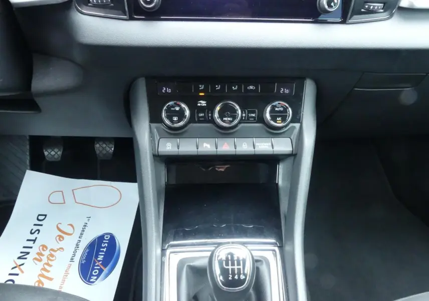 Vue rapprochée de la console centrale noire du Skoda Karoq blanc 2024, avec levier de vitesses manuel et commandes climatisation.