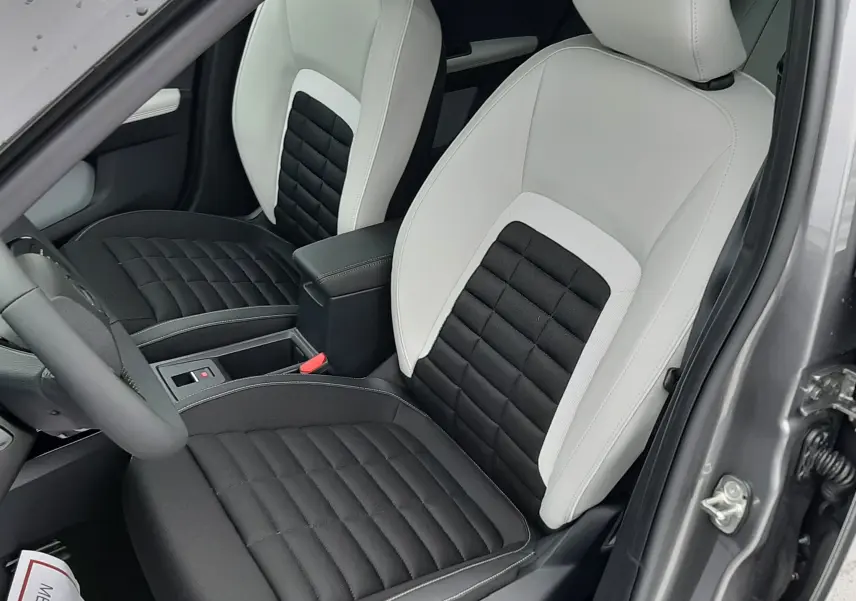 Vue intérieure côté conducteur du Citroën C3 Aircross hybride 2025, sièges bicolores noir et gris avec coutures apparentes.