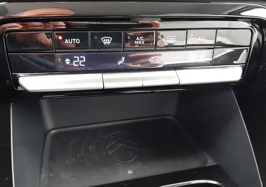 Panneau de commande de climatisation tactile avec affichage digital et zone de recharge sans fil dans une Citroën C3 Aircross hybride 2025.