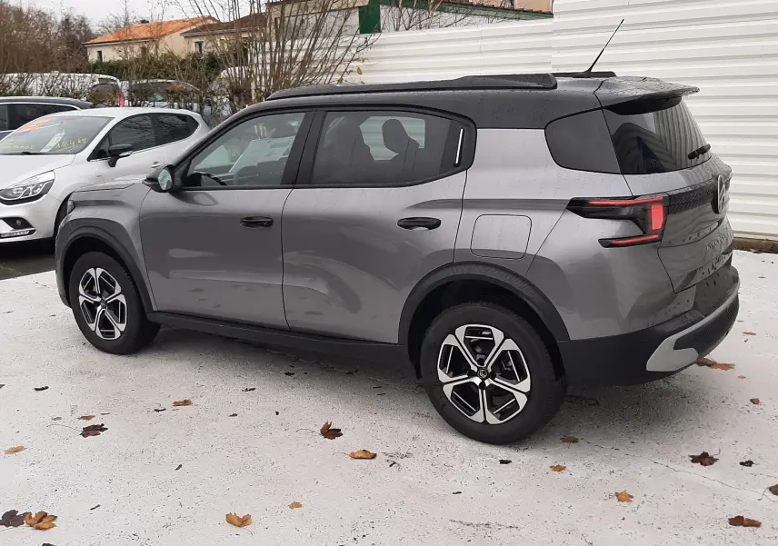 Vue 3/4 arrière droite d'une Citroën C3 Aircross hybride 2025 gris avec toit noir et jantes biton.