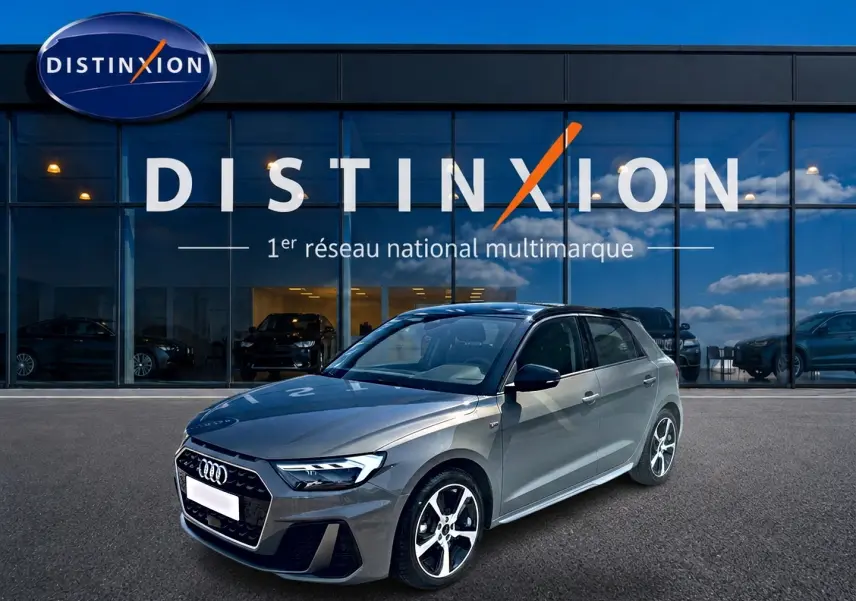 Audi A1 Sportback gris chronos vue 3/4 avant droit, avec jantes alu et toit noir devant vitrine Distinxion.