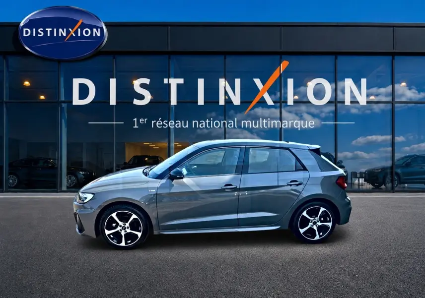 Audi A1 Sportback gris chronos vue de profil côté gauche, avec jantes alu et toit noir devant showroom Distinxion.