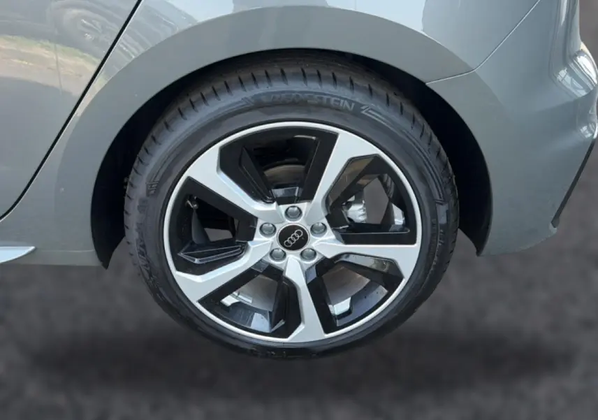 Gros plan sur la roue arrière droite d'une Audi A1 Sportback gris chronos avec jante alu bicolore.