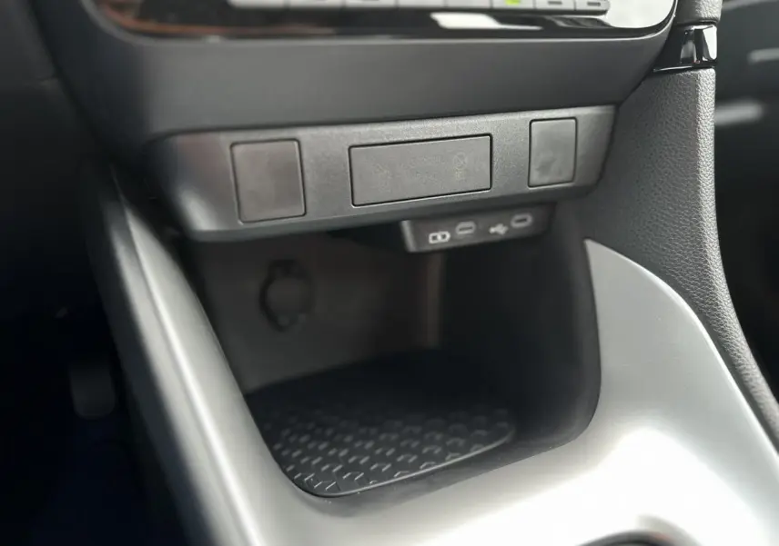 Gros plan sur la console centrale de la Toyota Yaris Hybride 2025 montrant les ports USB-C et un rangement noir mat.