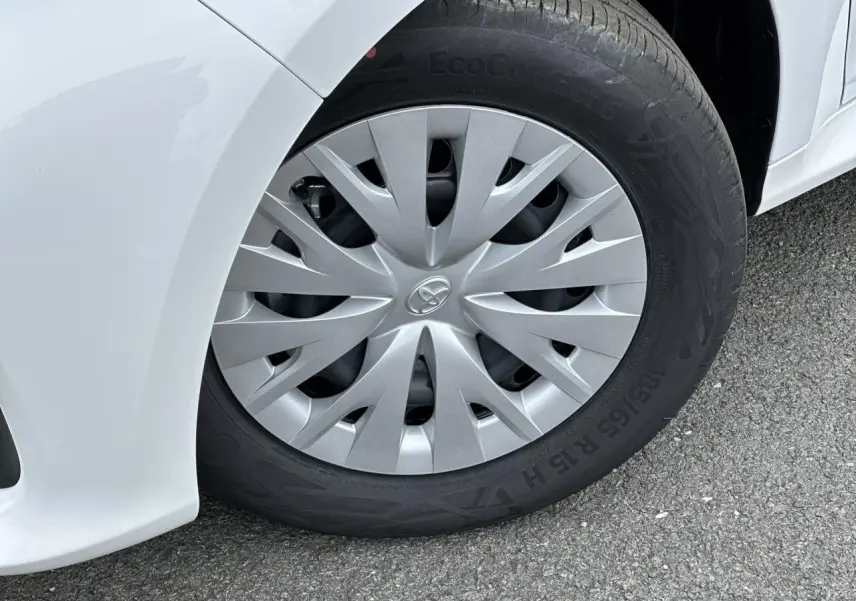 Gros plan sur la roue avant gauche d'une Toyota Yaris blanche Pure, avec enjoliveur gris et pneu EcoContact 6.