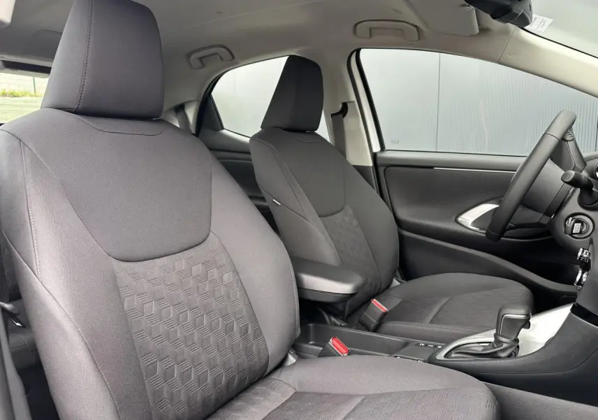 Intérieur de la Toyota Yaris Hybride 2025 montrant les sièges tissu noir et accoudoir central côté conducteur.
