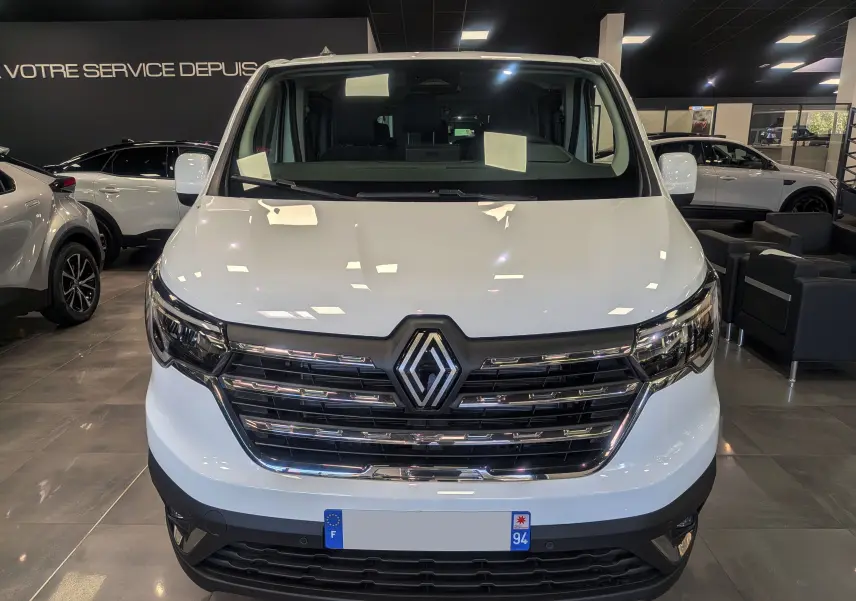 Vue frontale du Renault Trafic Combi blanc glacier, mettant en valeur la calandre chromée et le logo central distinctif.