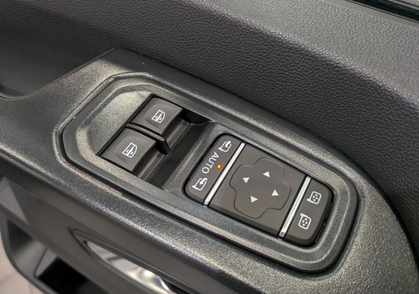 Gros plan sur les commandes électriques des vitres et rétroviseurs côté conducteur du Renault Trafic Combi blanc Glacier 2025.