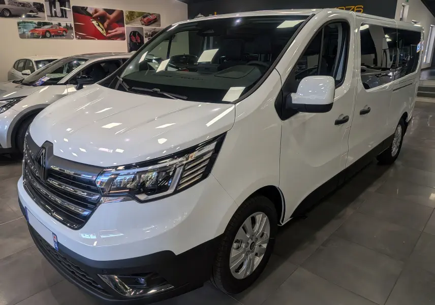 Renault Trafic Combi blanc glacier vu en 3/4 avant droit, avec calandre chromée et vitres teintées arrière.
