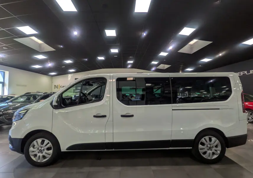 Profil côté gauche du Renault Trafic Combi blanc glacier 2025, montrant ses grandes fenêtres teintées et ses jantes alliage.