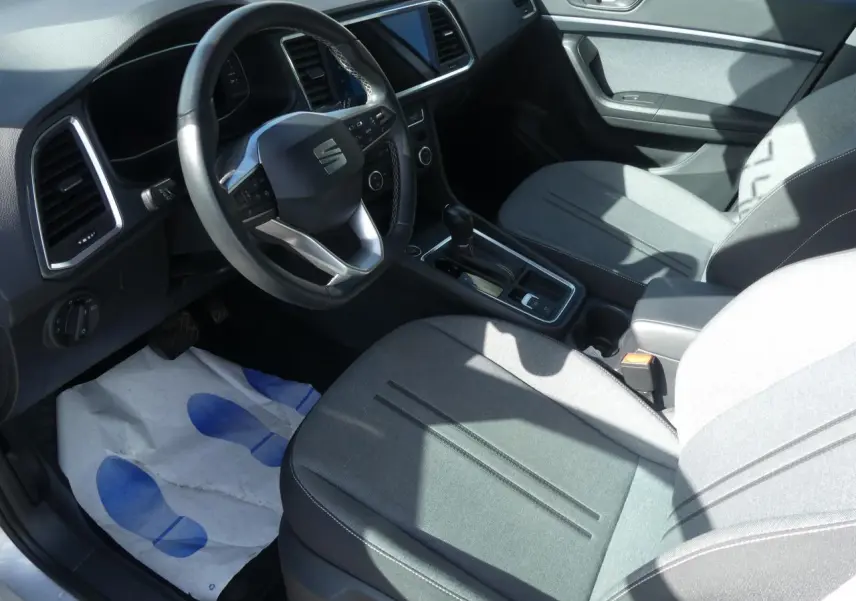 Intérieur avant droit d'un SEAT Ateca gris clair, volant cuir multifonctions et sellerie textile grise visible.