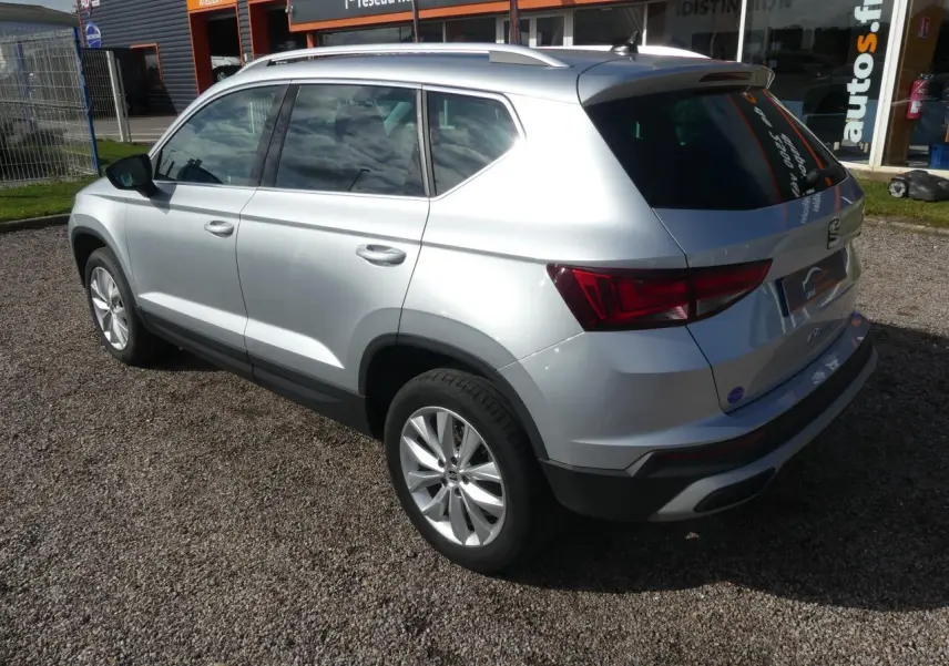 Vue 3/4 arrière droite d'un SEAT Ateca gris clair avec jantes alliage 17'' et vitres arrière surteintées.