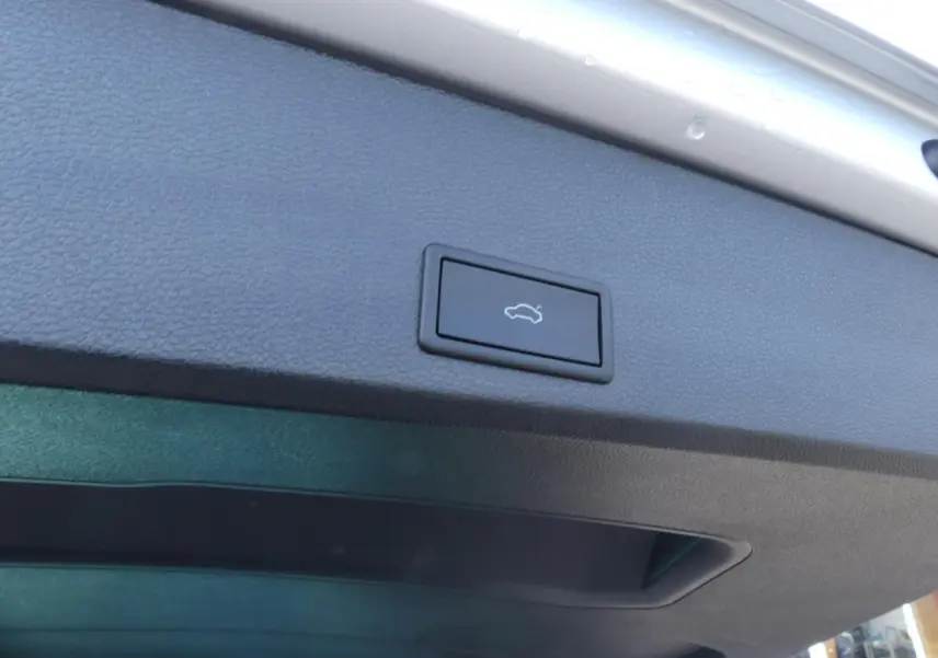 Bouton d'ouverture électrique du hayon sur la face intérieure du coffre d'un SEAT Ateca gris clair 2023.