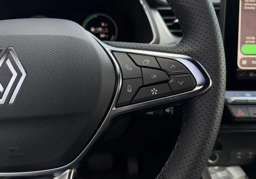 Gros plan sur le volant perforé noir du Renault Captur 2026 avec commandes intégrées et logo Renault central.