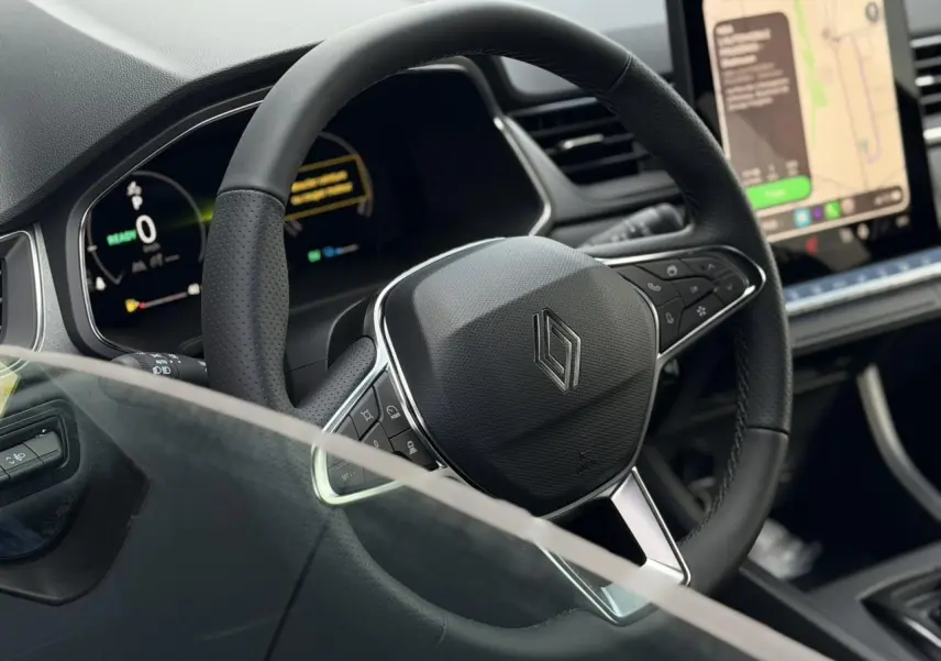 Vue rapprochée du volant noir texturé du Renault Captur 2026 avec tableau de bord numérique et écran tactile visible.