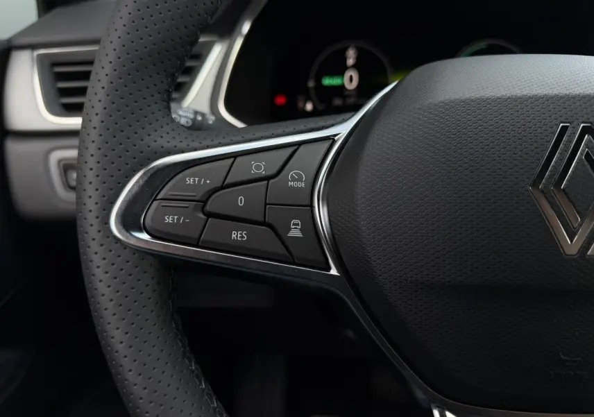 Gros plan sur le côté gauche du volant noir perforé du Renault Captur 2026 avec commandes intégrées et logo Renault central.