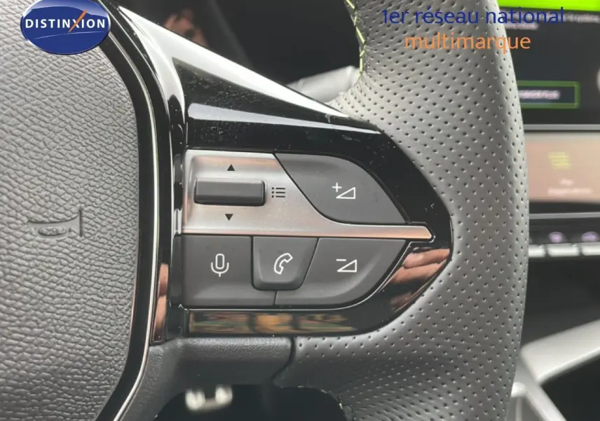 Gros plan sur les commandes gauche du volant perforé d’une Peugeot 308 gris selenium, avec boutons de volume et téléphone.