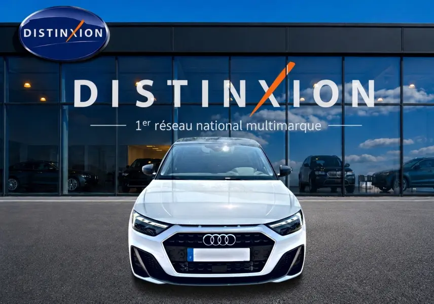 Audi A1 Sportback blanc et noir vue de face, avec calandre noire et logo Audi, devant une vitrine Distinxion.
