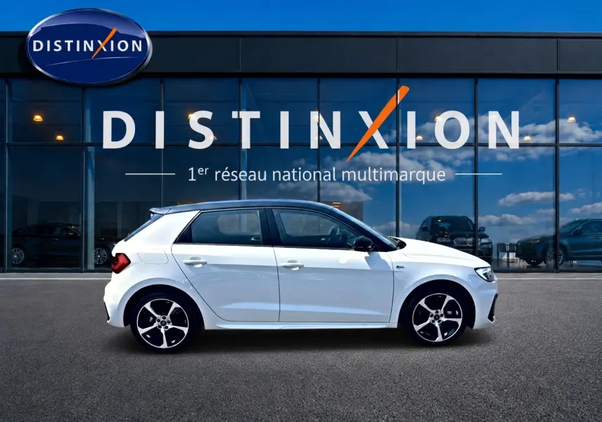 Audi A1 Sportback blanc et noir vue de profil côté gauche, avec jantes alu et toit noir devant vitrine Distinxion.