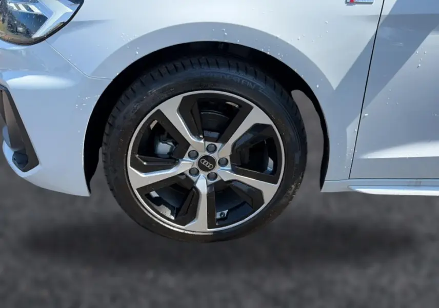 Gros plan sur la roue avant droite et l'aile blanche d'une Audi A1 Sportback 30 TFSI S line 2026 avec jante alu bicolore.