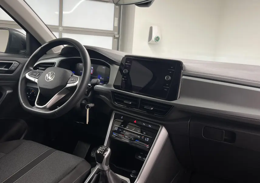 Intérieur du Volkswagen T-Roc 2024, vue côté conducteur montrant le volant, tableau de bord et levier de vitesse manuel.