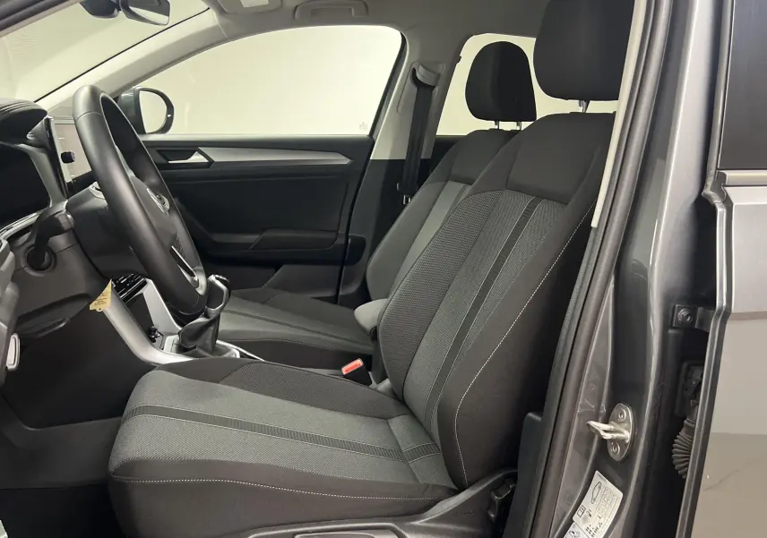 Vue intérieure côté conducteur du Volkswagen T-ROC gris Indium 2024, montrant les sièges avant et le volant.