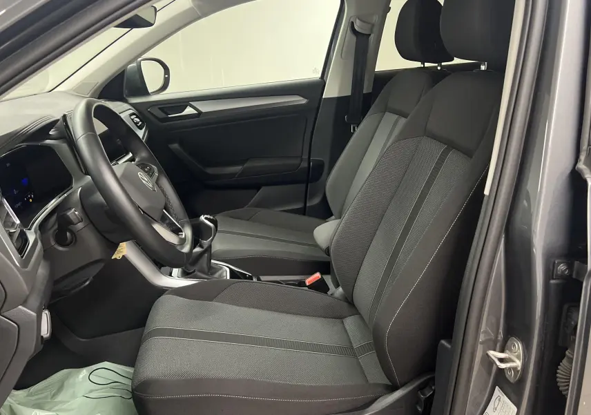 Vue intérieure côté conducteur du Volkswagen T-Roc 2024 gris Indium avec sièges tissu et volant multifonction.